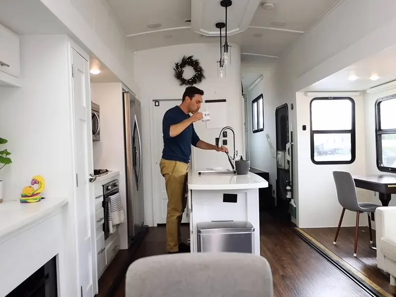 Andy Bailey stands at the counter of a bright camper kitchen, a dining nook behind him